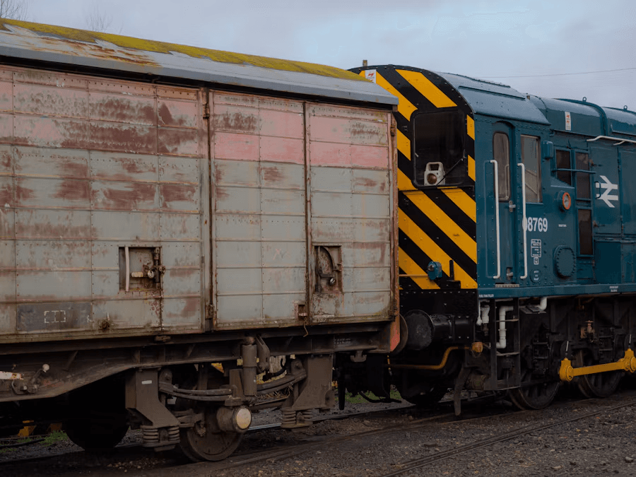 A blue diesel shunting locomotive with yellow and black warning stripes coupled to a weathered freight wagon.